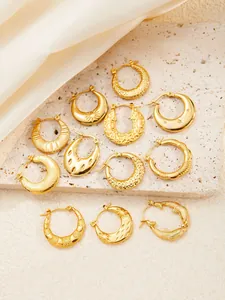 Detailed view of textured gold hoop earrings with sun and moon patterns on stone