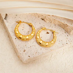 Golden titanium steel C-hoop earrings with star relief and matte texture on stone surface