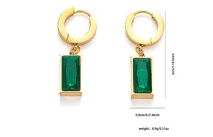 Detailed shot of gold earrings featuring emerald-cut green gems and precise engraving