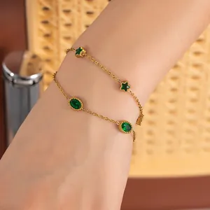 Detail of double-layer gold chain bracelet with green star and oval gemstones