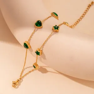 Close-up of gold double-layer chain bracelet with green heart and star zircon charms