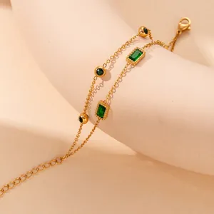 Detail showing golden double-layer bracelet with emerald-green gems on curved pedestal