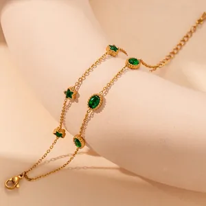 Close-up of golden double-layered chain with emerald green star and oval gemstones