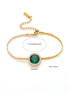Dettaglio del bracciale dorato con gemma verde rotonda e contorno di cristalli luccicanti