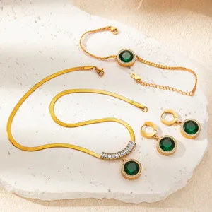 Elegant gold titanium necklace and jewelry set with emerald green stones on white marble