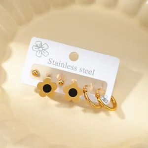 Ohrring-Set aus goldenem Edelstahl mit Sonnenblumen- und Kreuzmotiven in einer Schale
