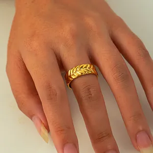 Gros plan détaillé d'une bague dorée avec texture épi de blé sur un doigt