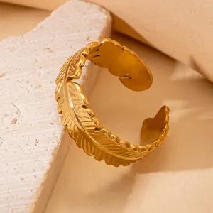 Detailed view of golden feather pattern engraving on a stainless steel open ring