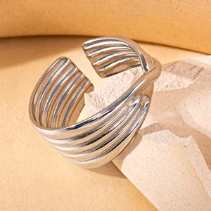 Detailed view of silver stainless steel open ring with layered textured patterns on rock