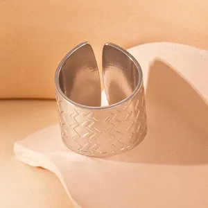 Nahaufnahme eines breiten Edelstahlrings mit Wellenmuster auf beigefarbenem Sockel