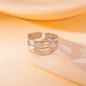 Detail van een minimalistische zilveren dubbellaagse ring met een unieke golfstructuur