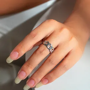 Close-up of a polished silver Cuban link chain ring worn on a finger in a lifestyle setting