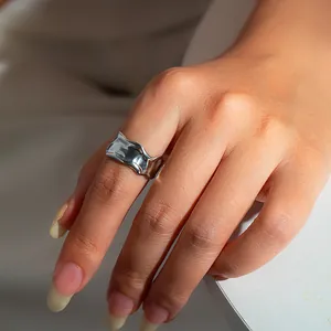 Close-up of minimalist silver irregular lava texture ring worn on the index finger