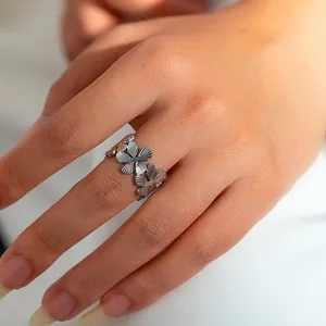 Close-up van een zilveren holle bloemring met geborstelde textuur aan de vinger