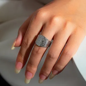 Detailed view of silver Saint Benedict medal ring with religious engravings and textured band