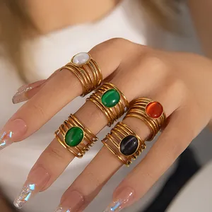 Close-up of multilayer gold titanium steel rings with colorful oval gemstones on hand