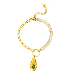 Detail of gold stainless steel bracelet with feather pendant and green teardrop zircon