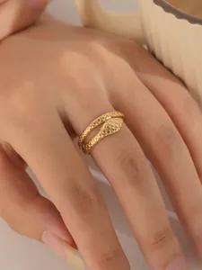 Detailansicht eines goldenen Schlangenrings mit Schuppentextur am Finger