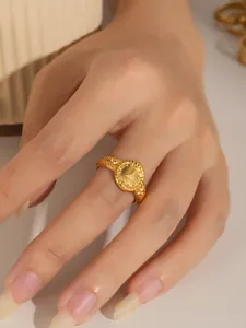 Detalle de anillo estilo reloj vintage dorado con patrones grabados y relieve fino