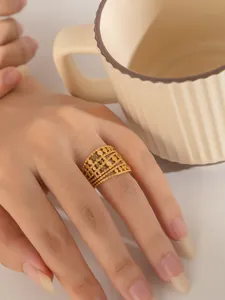 Makroaufnahme eines breiten goldenen Edelstahlrings mit hohlen Schichten an einem Finger