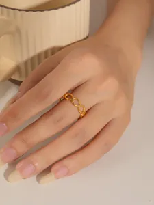 Vista detallada de un anillo de cadena dorado de acero de titanio en una mano elegante