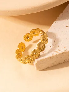 Detail eines verstellbaren Gänseblümchen-Rings aus Gold auf Stein mit feiner Textur