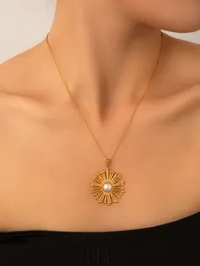 Dettaglio della collana in acciaio al titanio dorato con ciondolo a sole e perla bianca