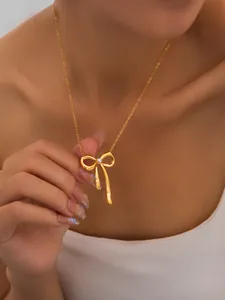 Close-up of elegant gold bow pendant necklace with pearl on woman's neck