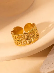 Detail eines goldenen, hohlen Kettenrings auf Keramikdisplay mit natürlichem Design