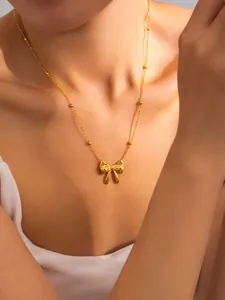 Close-up of golden bow-shaped pendant necklace on a woman's neck for a warm aesthetic