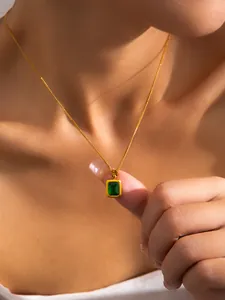 Detailed close-up of a gold necklace featuring a green rectangular gemstone pendant