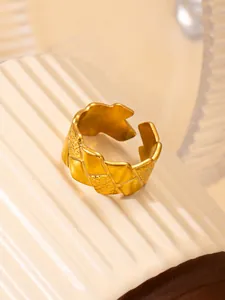 Detalle del anillo de acero de titanio dorado con textura tejida geométrica y acabado mate