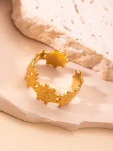 Detalle del anillo de margaritas doradas ajustable sobre una superficie de piedra natural