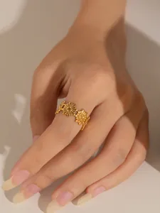Detalle de anillo de girasol dorado en acero de titanio con diseño floral en el dedo