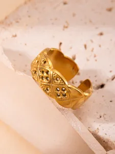 Detalle macro de anillo de acero de titanio dorado con patrón de diamantes acolchados