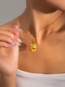 Detailed view of a gold pearl necklace with a spiral swirl pendant on a female model