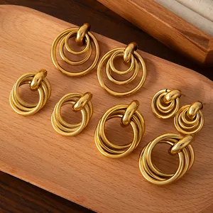 Makroaufnahme verschiedener goldfarbener Edelstahl-Ohrringe auf einem Holzdisplay