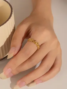 Detalle de anillo dorado calado con forma de hoja en dedo índice y acabado mate elegante