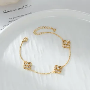 Bracciale a quadrifoglio dorato con zirconi su un piatto bianco effetto acqua