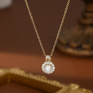Vue rapprochée du pendentif en perle baroque avec halo de zircons sur chaîne dorée