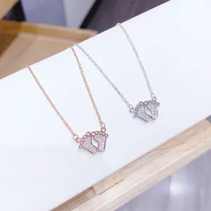 Close-up of rose gold and silver baby feet pendants with sparkling zircon pavé