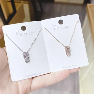 Detailansicht von Flip-Flop-Anhängern in Silber und Roségold mit weißem Strassbesatz