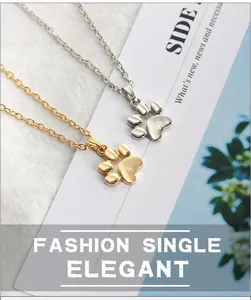 Detailed view of elegant gold and silver paw print necklaces on a textured fabric