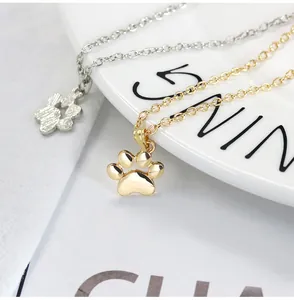 Close-up of cute solid gold and silver cat paw pendant necklaces on a white ceramic plate