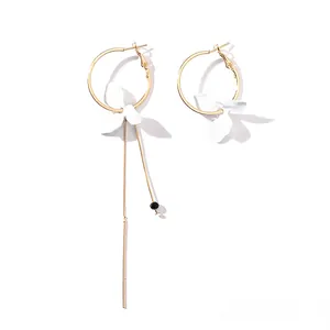 Vue détaillée de boucles d'oreilles asymétriques dorées avec longs pompons et motifs floraux