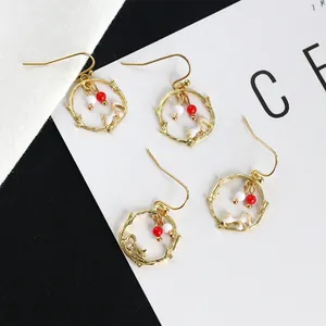 Pendientes asimétricos dorados de rama con dijes de conejo blanco y cuentas de color