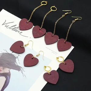 Pendientes de corazón de madera roja con cadenas largas doradas en revista de moda