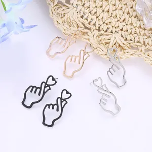 Three pairs of heart gesture hollow metal earrings in gold, silver, and black finish