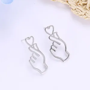 Detailed close-up of silver finger heart earrings with hollow heart on white surface