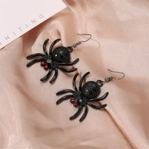 Gothic spider dangle earrings with red rhinestone eyes on champagne silk fabric background